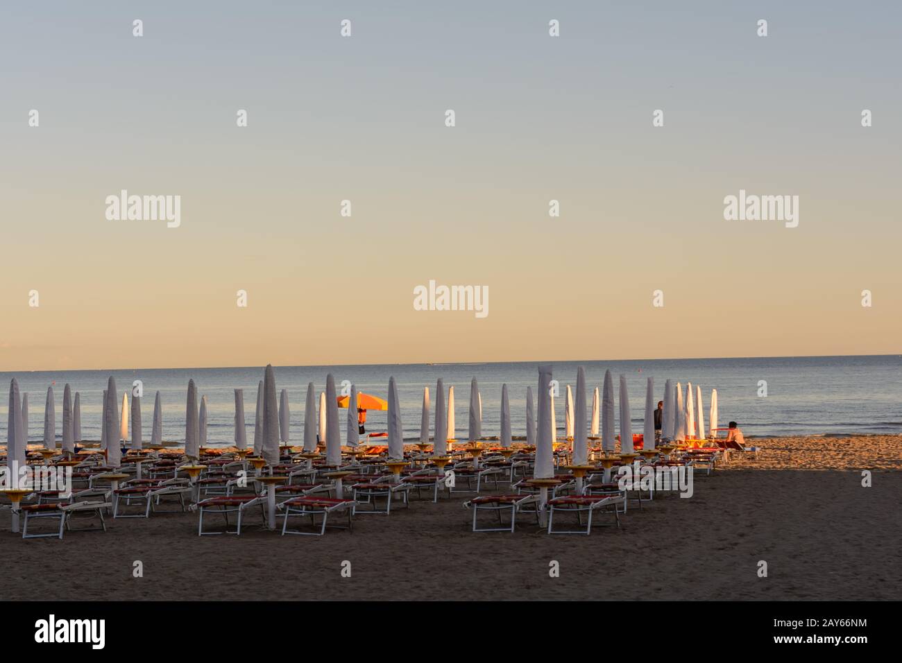 Geschlossene Sonnenschirme und Sonnenliegen am Strand in Italien Stockfoto