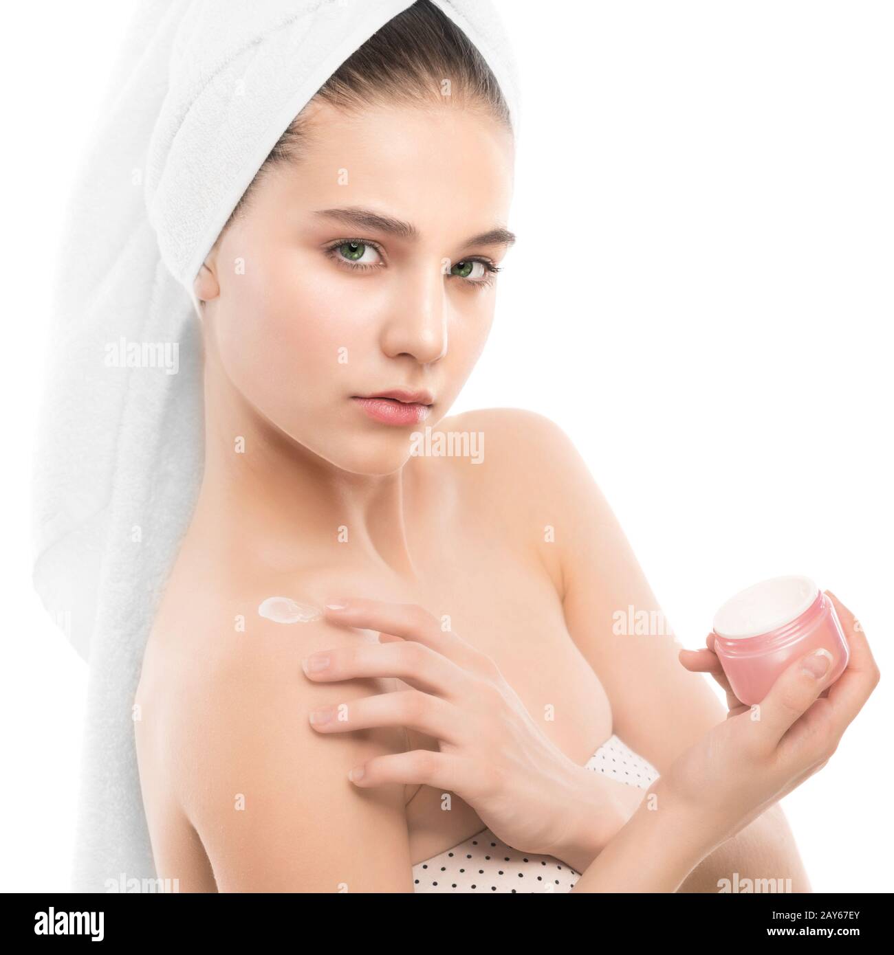 Frau mit sauberem Gesicht und ein Handtuch auf dem Kopf Anwendung Feuchtigkeits-creme an den Schultern. Isoliert. Stockfoto