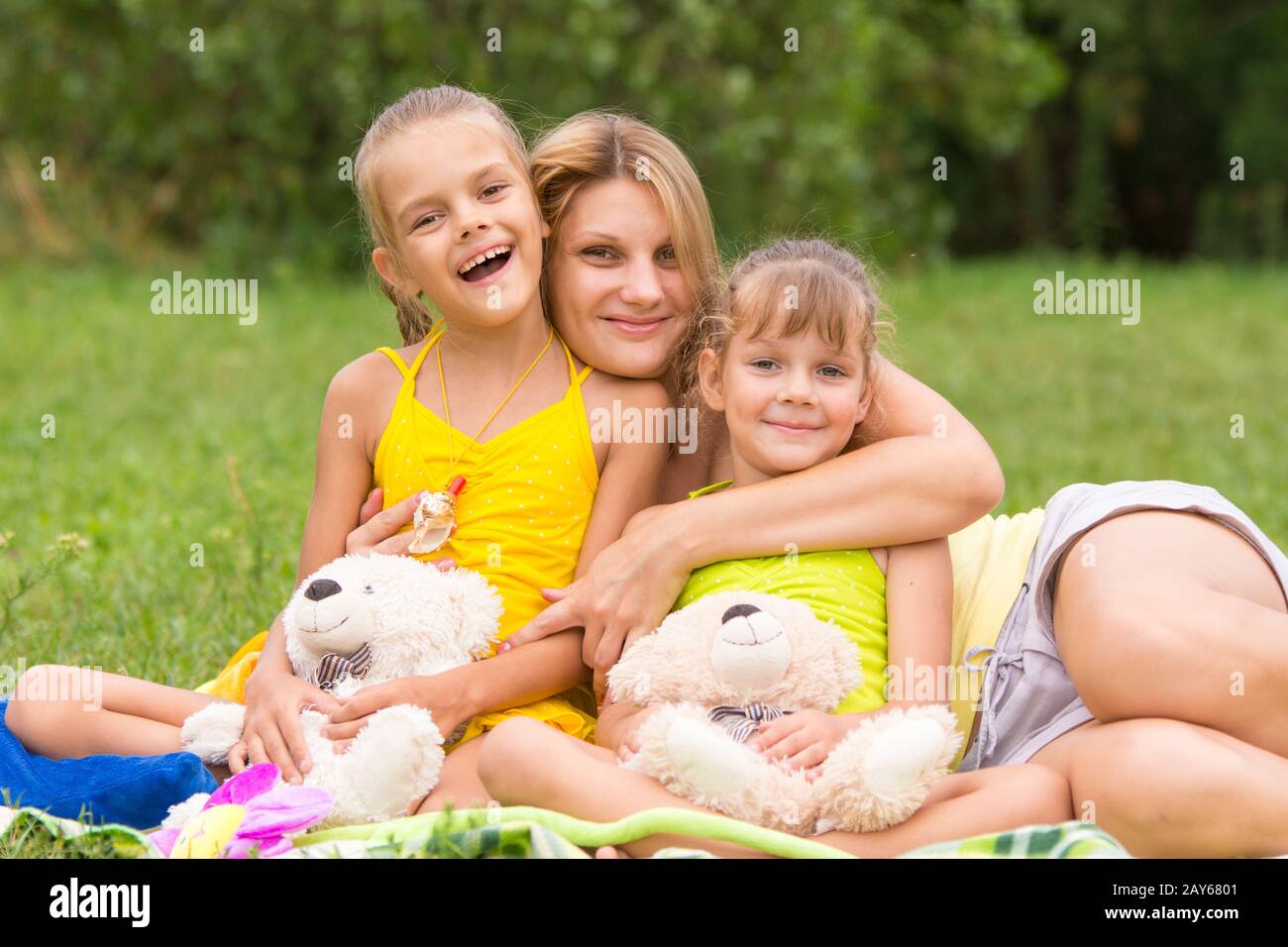 Junge Mutter auf ein Picknick umarmt, zwei Töchter, fünf und sieben Jahren Stockfoto
