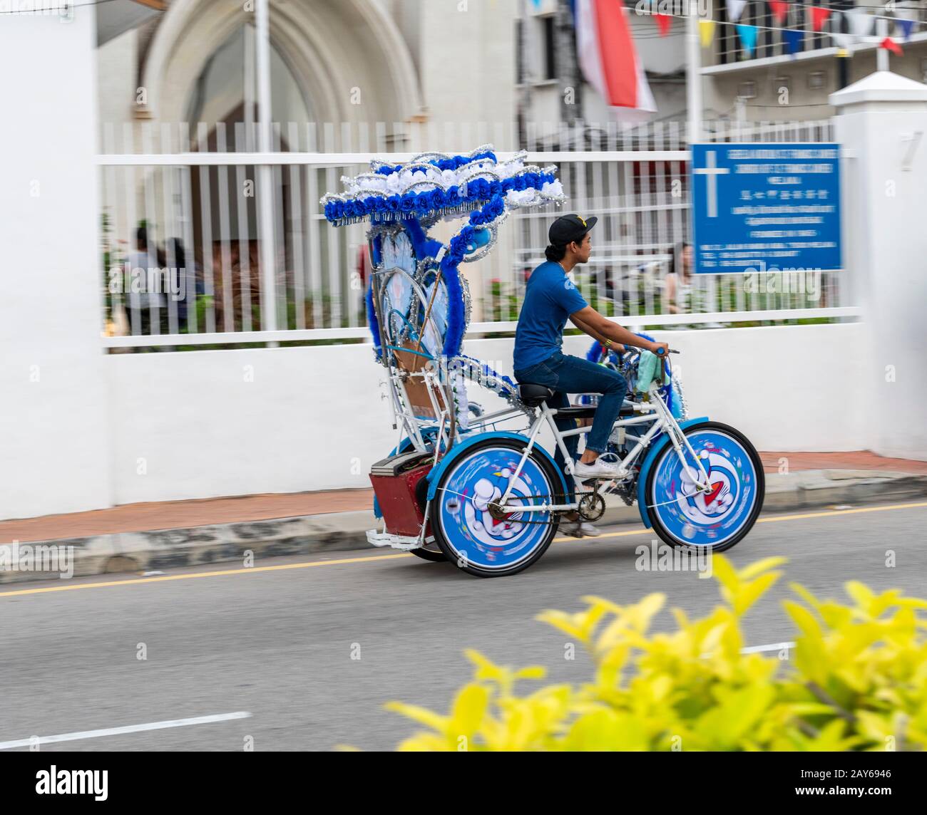 Trishaw Fahrer vor der St. Francis Xavier Kirche in Melacca, Malaysia. Ein muss in Melacca fahren. Stockfoto