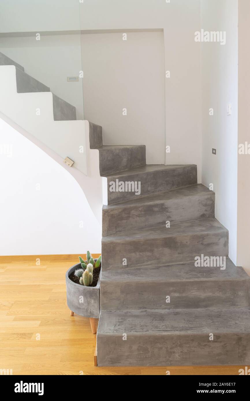 Microzement graue Farbe auf der Treppe mit mattem Finish, in Kombination mit weißen Wänden und natürlichem Holzboden Stockfoto