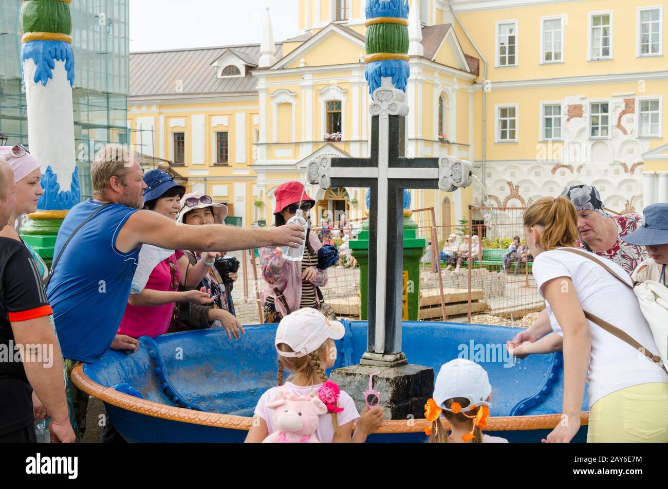 Sergiev Posad - 10. August 2015: Touristen gewinnen das Weihwasser in der Passage der Schüssel mit einem Kreuz in Svvyato Trinity Stockfoto