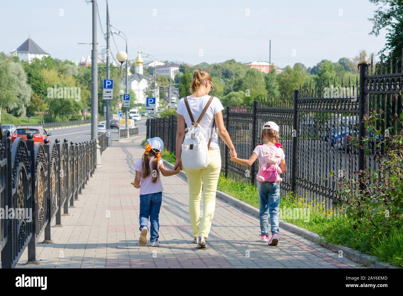 Mutter und zwei Töchter sind auf dem Bürgersteig entlang der Straße Stockfoto