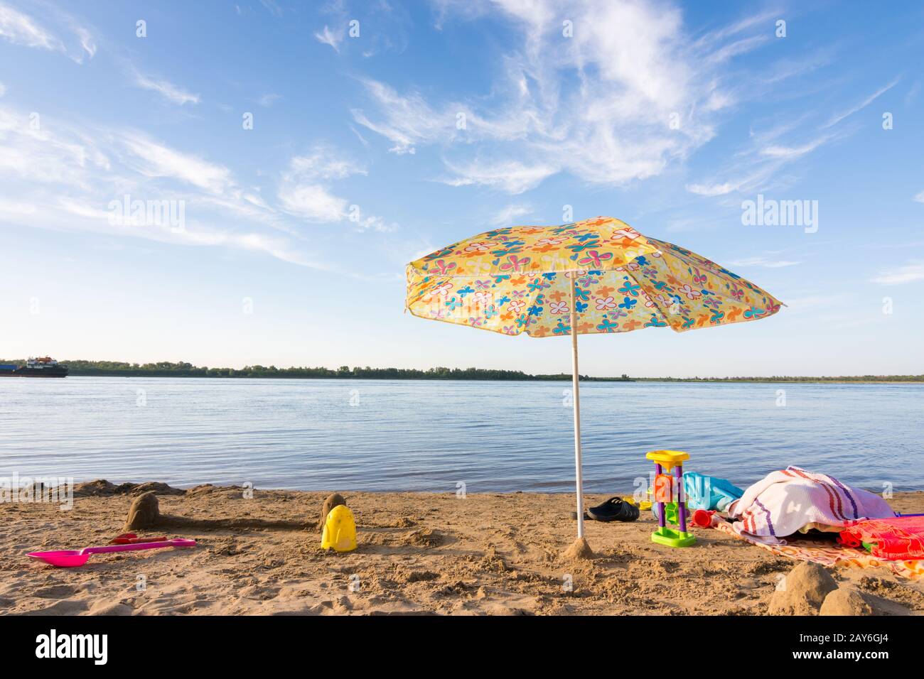 Sonnenschirm am Ufer Flusses, unter denen die verstreuten Gegenstände und Spielzeug Stockfoto