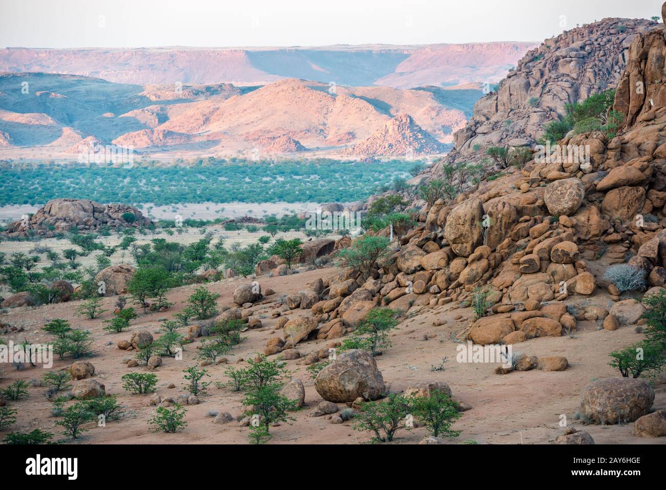 Felsige Landschaft von Namibia mit riesigen Felsbrocken und grünen Bäumen Stockfoto