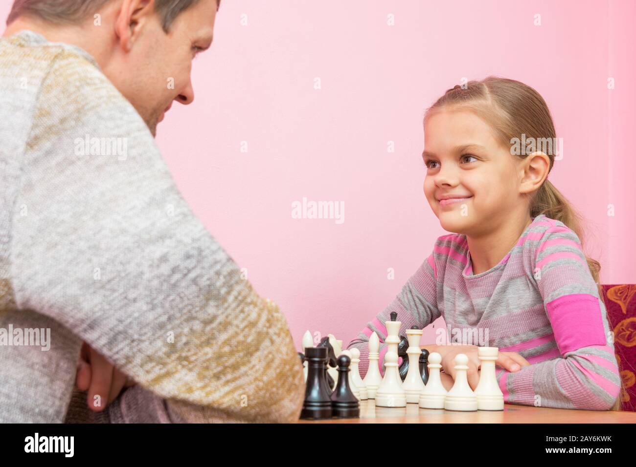 Vater und Tochter schauen gerne einander, spielen Schach Stockfoto