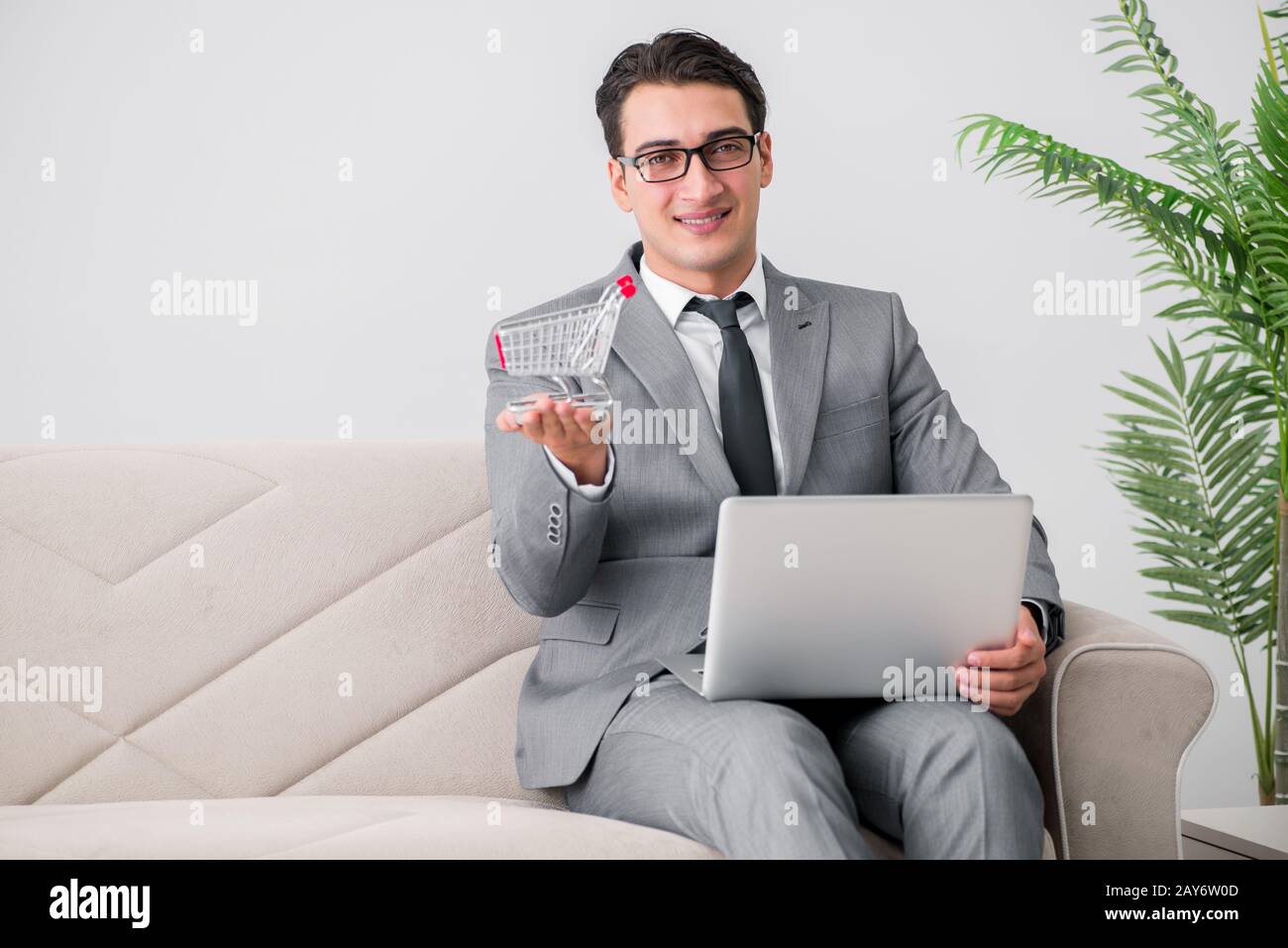 Geschäftsmann mit Laptop und Warenkorb Stockfoto