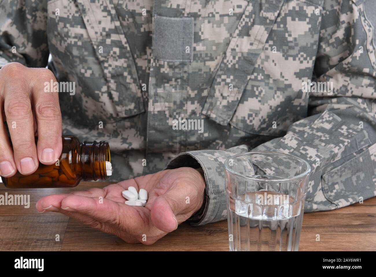 Konzept des militärischen Drogenmissbrauchs. Nahaufnahme des Soldaten mit der Einnahme von Pillen zur Behandlung seiner PTSD-Symptome. Stockfoto