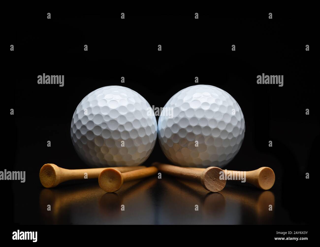 Golf Stillleben. Zwei Golfbälle mit T-Shirts, die auf einer schwarzen reflektierenden Oberfläche liegen. Niedriger Winkel mit Kopierbereich. Stockfoto