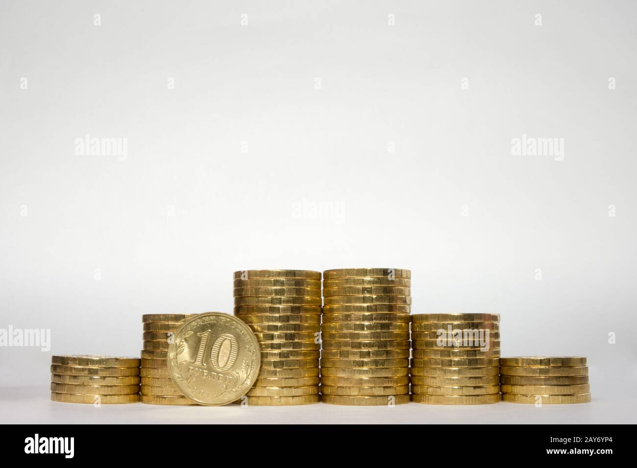 Sechs Münzstapel, die sich symmetrisch auf weißem Grund in die Höhe erhöhen, sticht mit einem Pockmarck am Rand des russischen 10 Rubel Stockfoto
