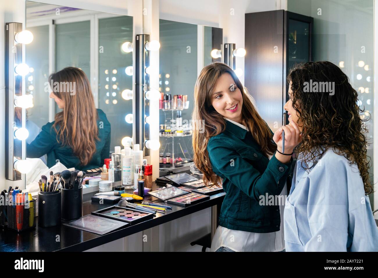 Professionelle Make-Up-Künstlerin, die einem schönen jungen Mädchen Make-up in die niedliche Studie macht Stockfoto