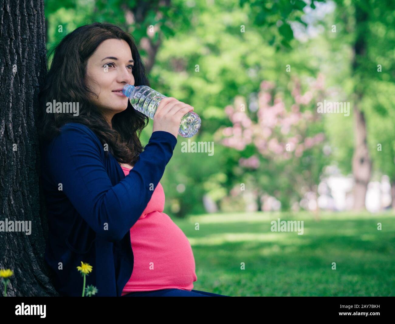 Schwangere Frau trinkt Wasser aus der Flasche Stockfoto