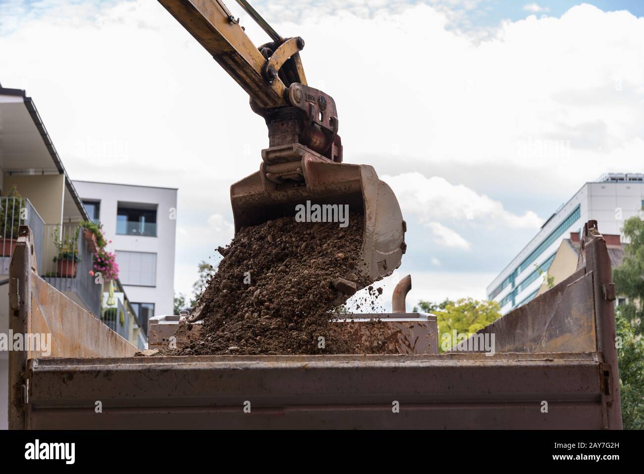 Der Schaufelbagger lädt Bauschutt auf einen LKW an einer Baustelle Stockfoto