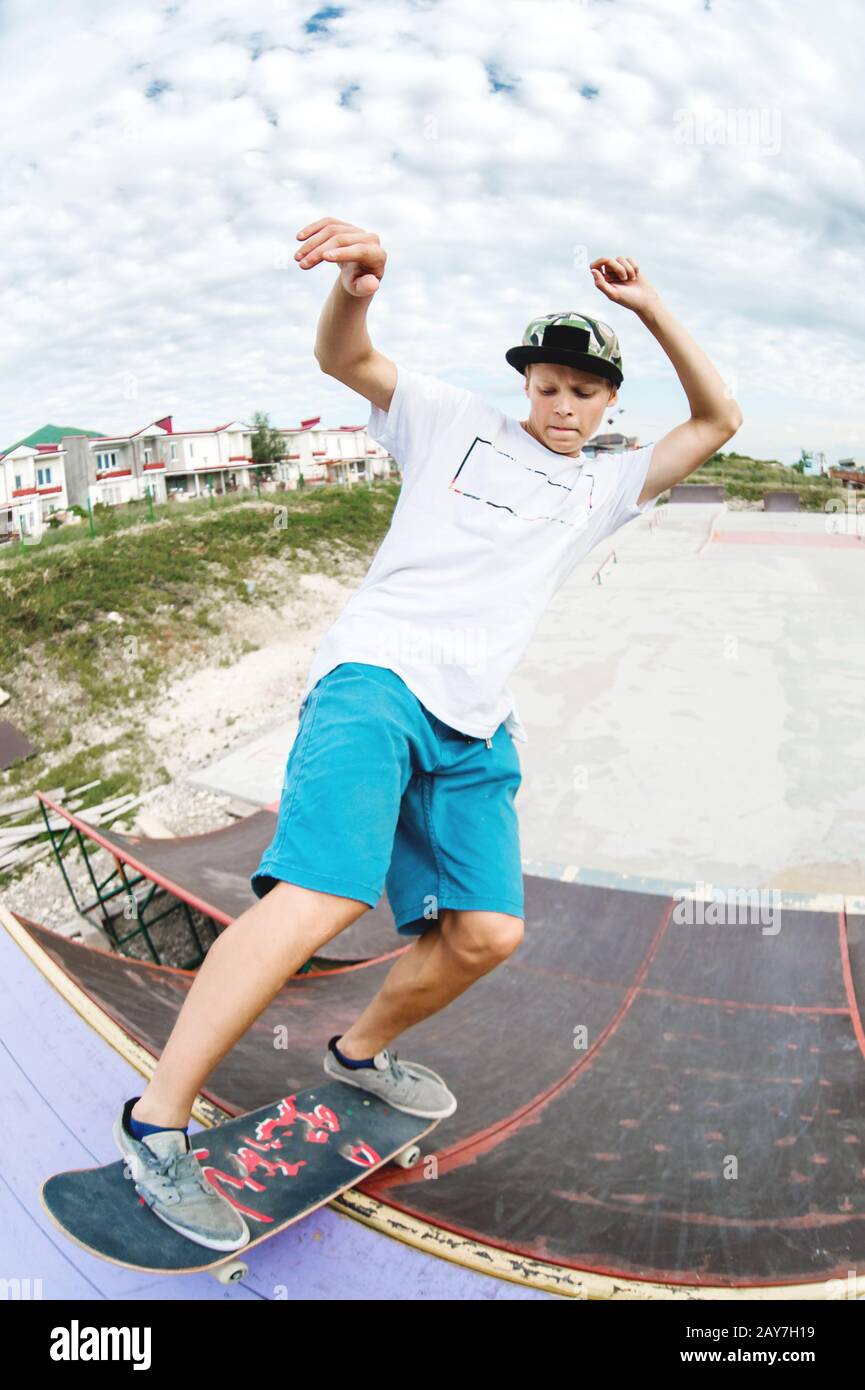 Teenager Skater hängen über eine Rampe auf einem Skateboard in einem Skatepark Stockfoto