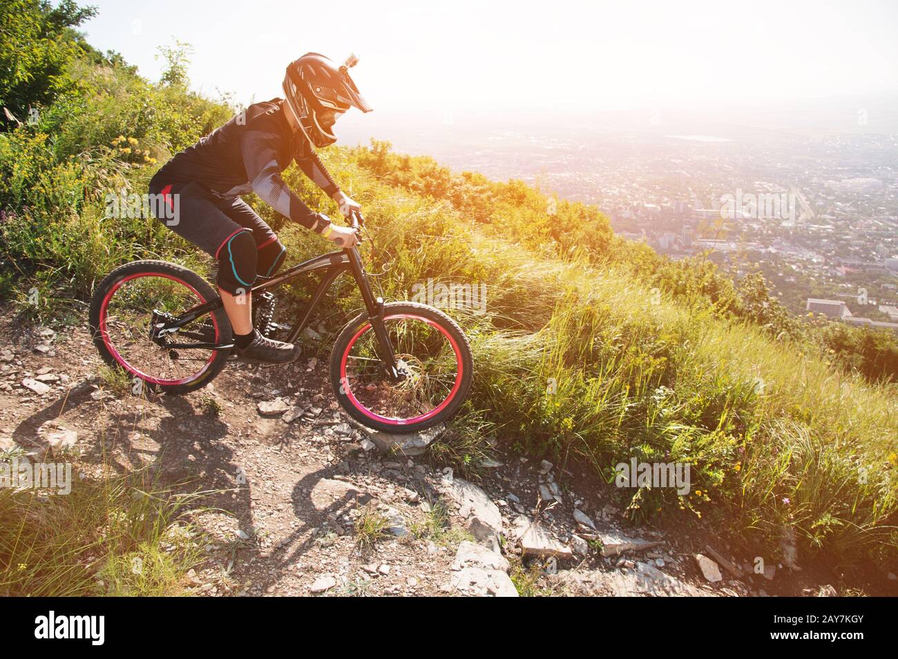 Ein Fahrer in einem Helm reitet auf einem Schotterweg von einem Berghang auf einem Mountainbike-Rad Stockfoto