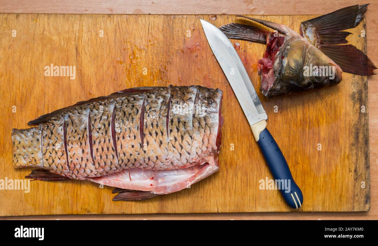 Die gebürstete und schneiden Fisch liegt auf dem Schneidbrett, daneben liegt ein Messer Stockfoto