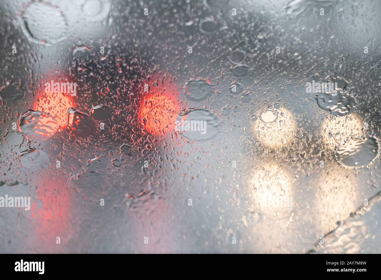 Starker Regen auf der Windschutzscheibe des Autos und außer Fokus gerichtete Scheinwerfer - Großbritannien Stockfoto