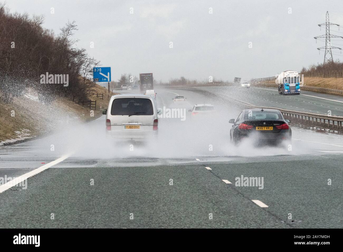 Autos, die auf der Autobahn M74 UK durch tiefe Pfütze fahren Stockfoto