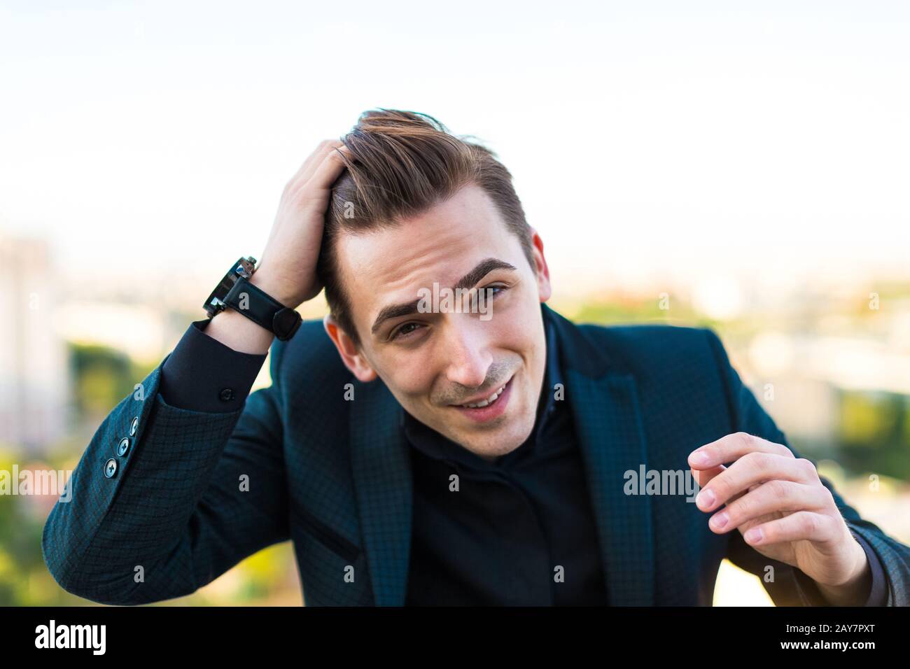 Junger seriöser Busunessman in dunklem Anzug, Armbanduhr und schwarzem Hemd ST Stockfoto