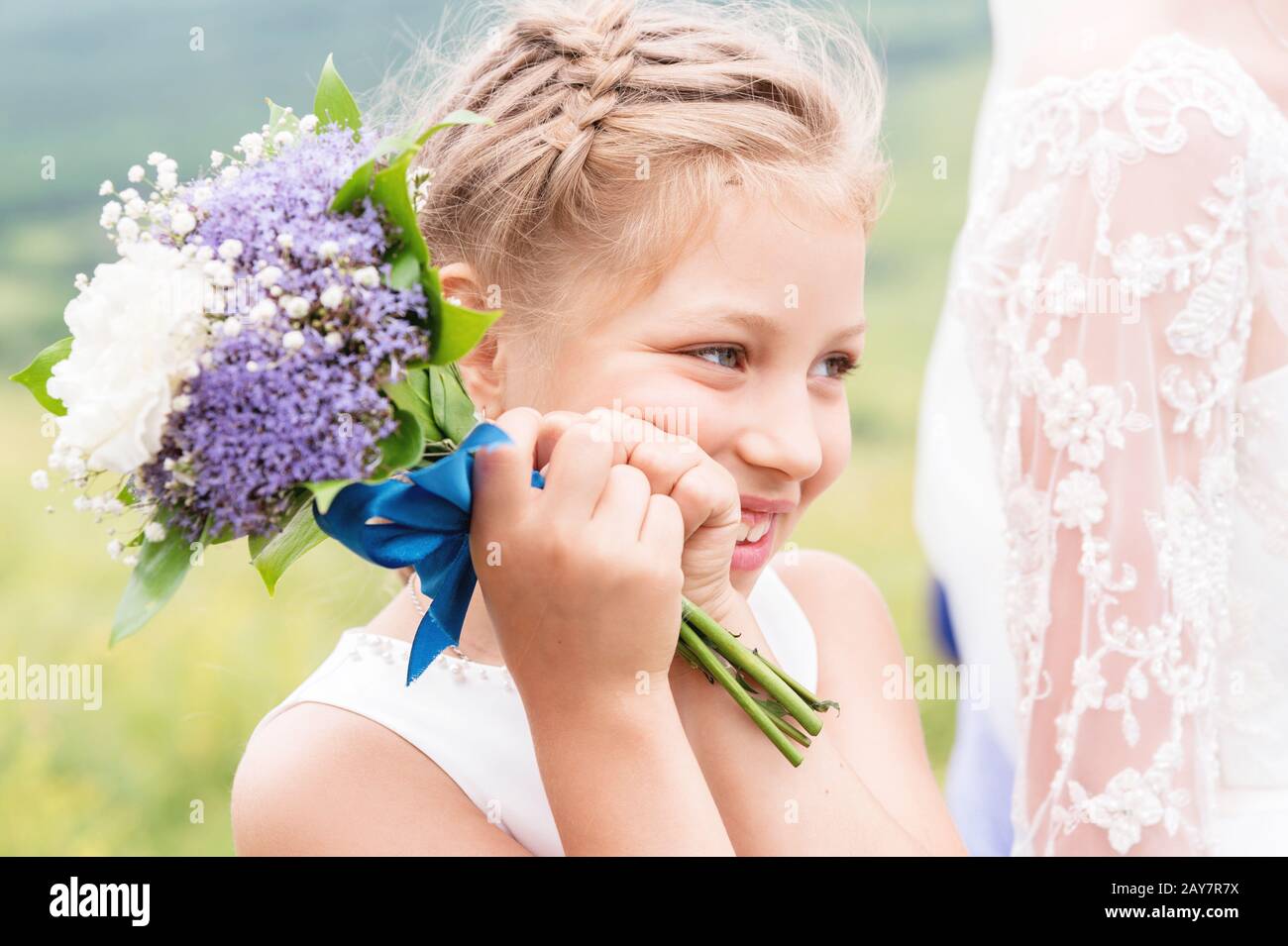 Ein süßes, wenig berührendes Kind und ein wunderschönes Blumenstrauß mit weißen und violetten Ponys bei der Hochzeit ihrer Eltern Stockfoto