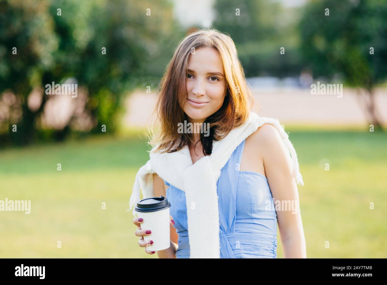 Foto einer hübsch aussehenden jungen Frau mit angenehmem Aussehen, verbringt das Wochenende im Freien, schlendern durch den Park, hält Papier Einweg-cu Stockfoto