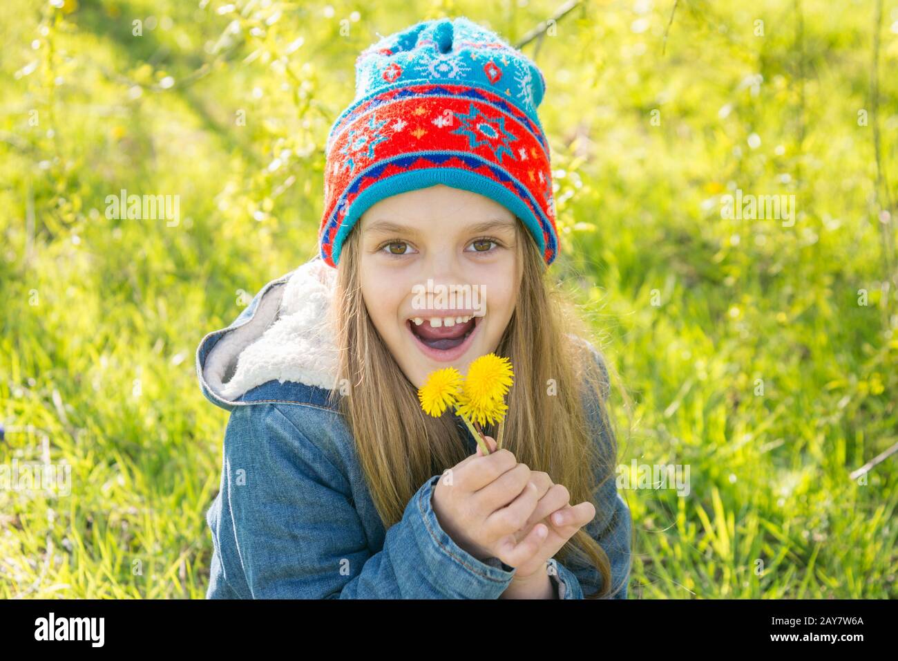 Sieben Jahre alten Mädchen in der Feder mit dem blühenden Löwenzahn erfreut Stockfoto