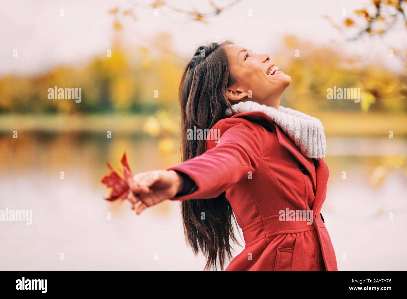 Herbstfrau glücklich lächelnd frei in Herbstnatur. Natur Menschen Schönheit Landschaft. Mädchen am See. Stockfoto