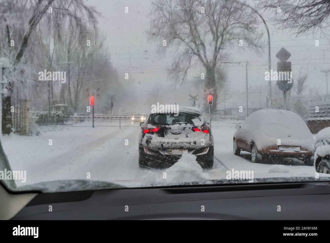 Vor geschlossenen Bahnsperren steht ein Auto in der Schneeflaube. Stockfoto