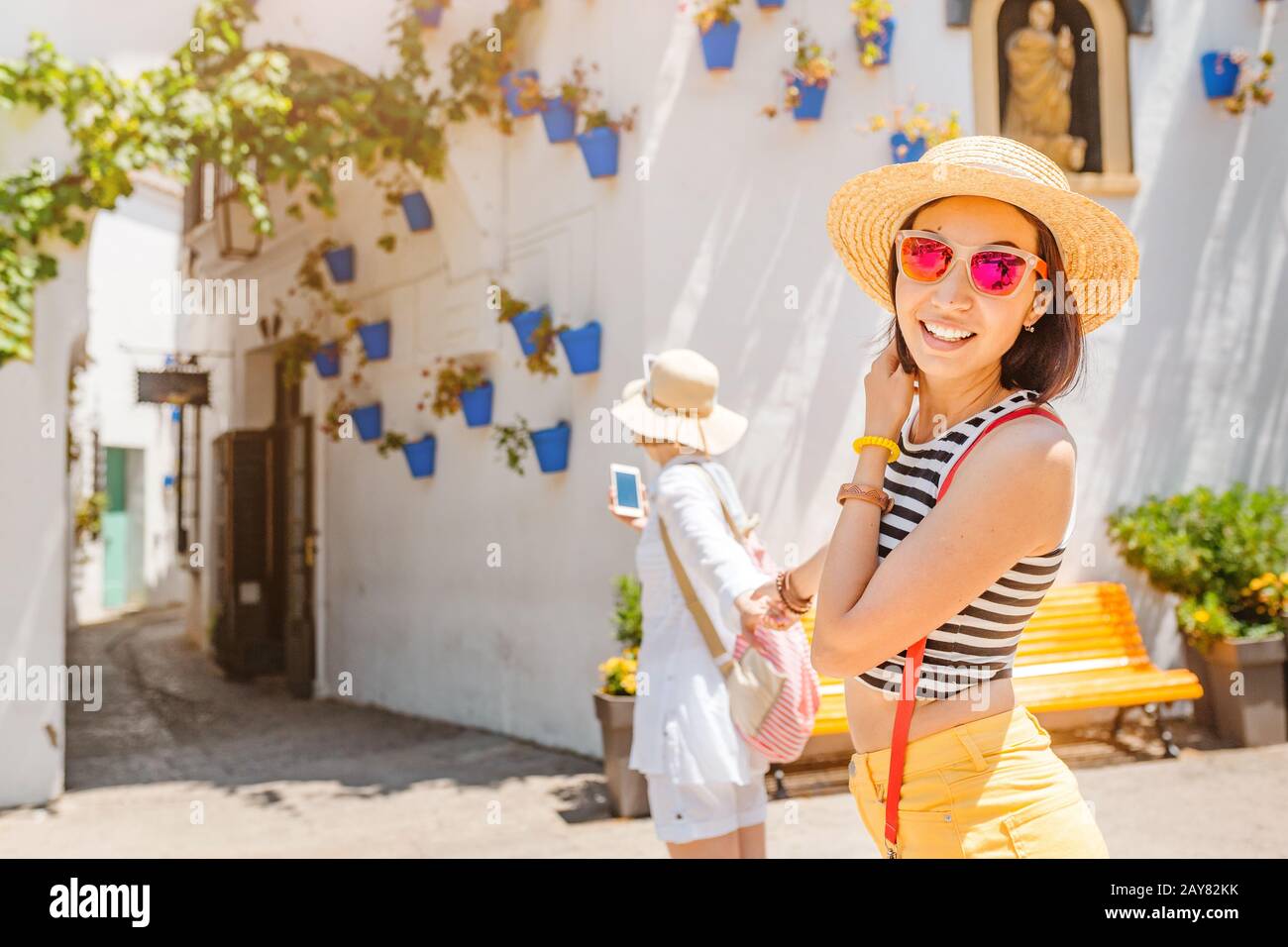 Zwei Mädchen Touristen bewundern einen tollen Blick auf Blumentöpfe an den weißen Wänden in der berühmten Blumenstraße in Andalusien Stockfoto