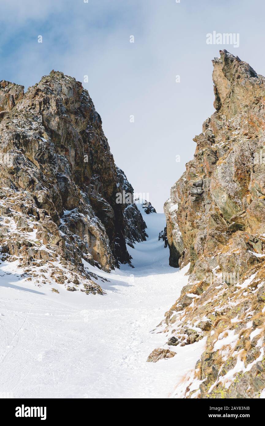 Nahaufnahme. Blick auf einen schneebedeckten Couloir zwischen scharfen Felsen. Stockfoto