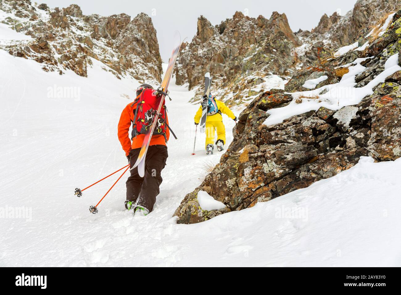 Extreme Skifahrer klettern auf den Gipfel entlang des Couloirs zwischen den Felsen vor dem Abstieg des Freeride-Rücklandes Stockfoto
