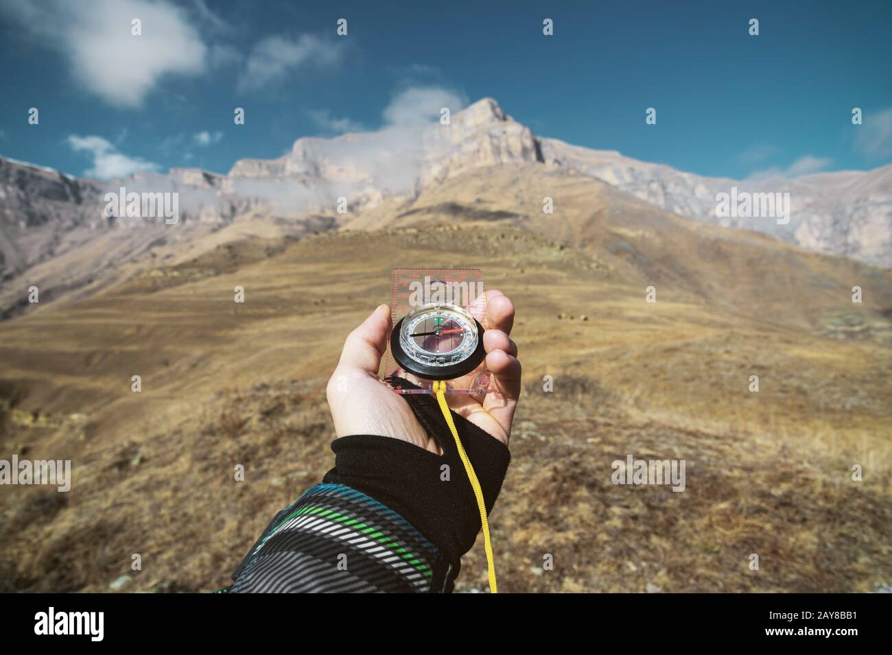 Blickpunktaufnahme. Ein erster Blick auf die Hand eines Mannes hält einen Kompass vor dem Hintergrund einer epischen Landschaft mit Klippenhügel Stockfoto