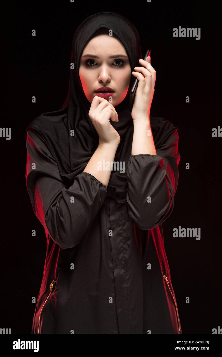 Porträt der schönen schweren Angst junge muslimische Frau mit schwarzen Hijab um Hilfe ruft auf schwarzem Hintergrund Angst Stockfoto