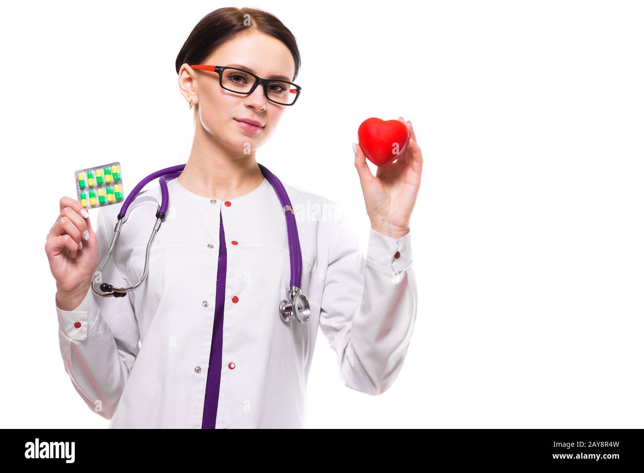 Junge schöne Frau Doktor halten Herz und Pillen in ihre Hände auf weißem Hintergrund Stockfoto