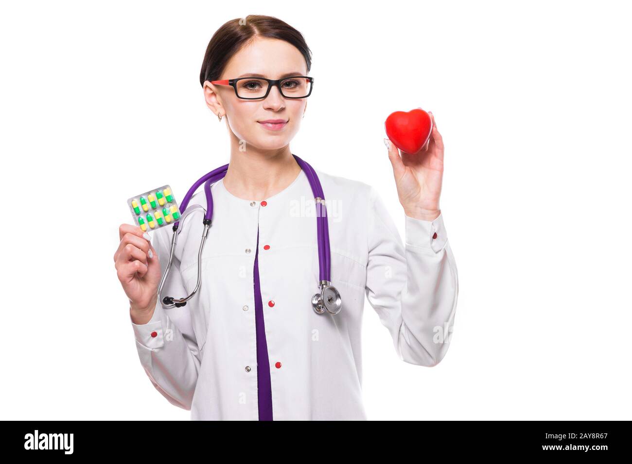 Junge schöne Frau Doktor halten Herz und Pillen in ihre Hände auf weißem Hintergrund Stockfoto