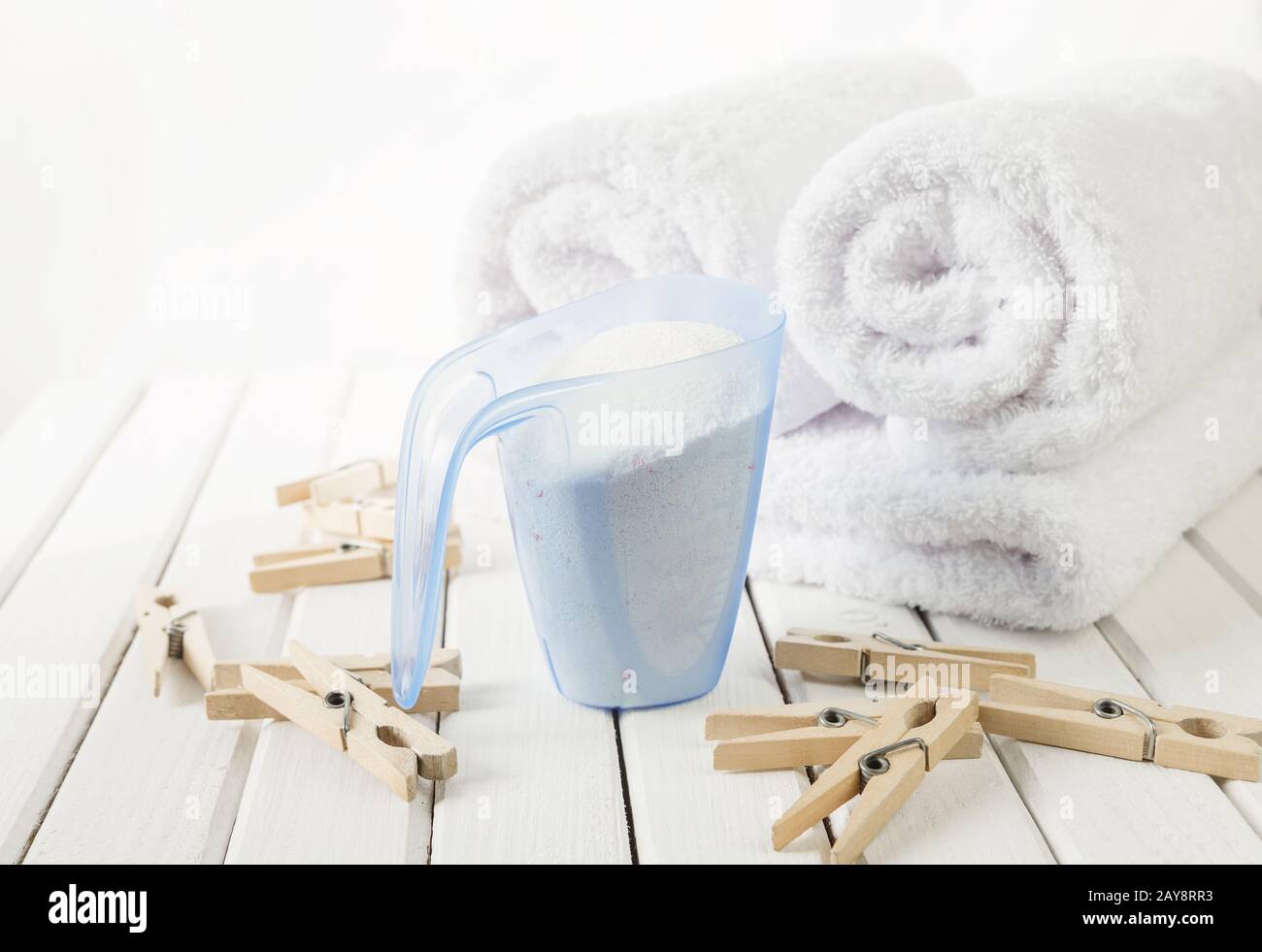 Handtücher, Waschpulver in Messbecher und Holzkleidereppen Stockfoto