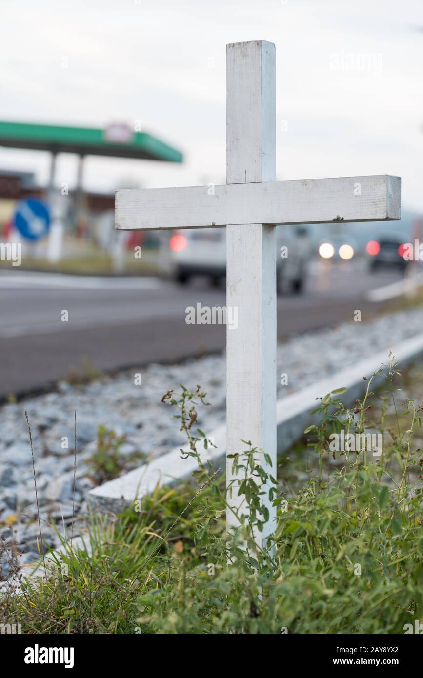 Warnschild mit weißem Kreuz am Straßenrand - Verkehrstote Stockfoto