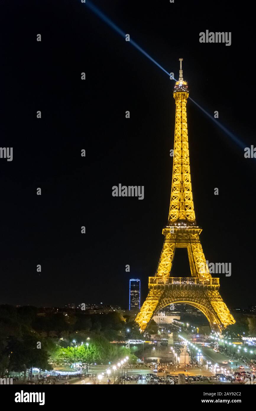 Zahlreiche Besucher schlendern an einem warmen Sommerabend durch den beleuchteten Eiffelturm in Paris. Stockfoto
