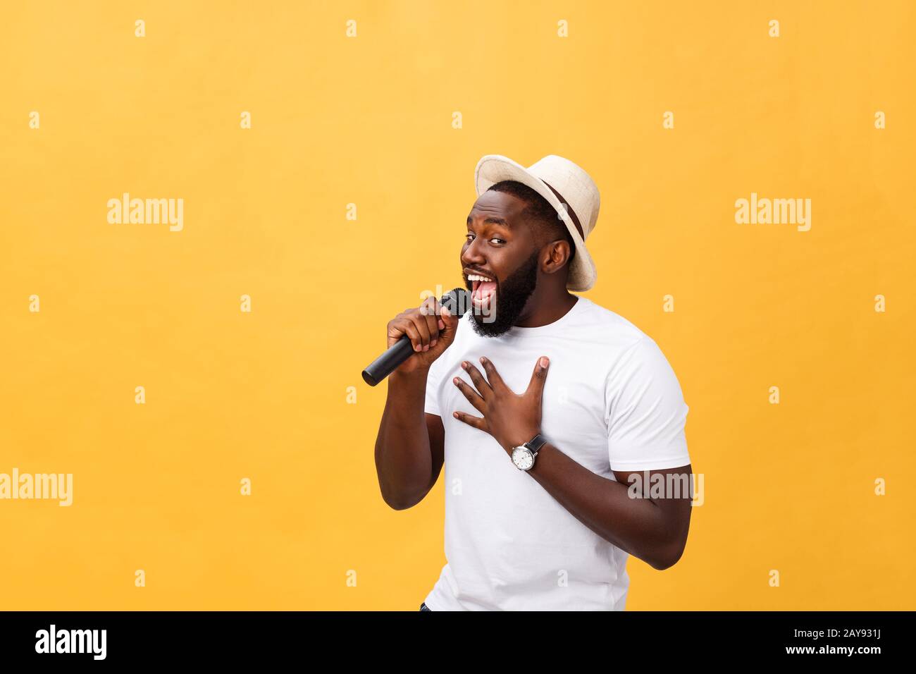 Junge schöne African American Boy singen emotionale mit Mikrofon auf gelbem Hintergrund isoliert, in Bewegung Gestik Stockfoto