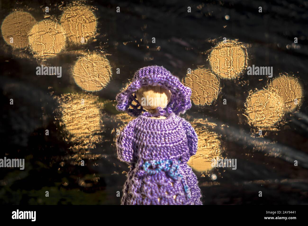 Puppe mit Gestricken blaues Kleid gegen verschwommenen Hintergrund mit hellen Lichtern Stockfoto