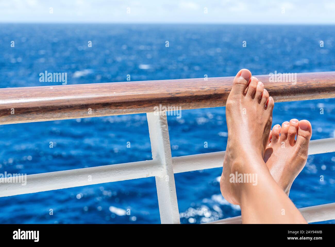 Entspannung auf Kreuzfahrtschiffreisen Urlaub. Die Lage der Frauen liegt auf dem Balkon mit Blick auf das Meer und den karibischen Urlaub auf dem Meer. Barfuß-Frau Sonnenbräunung entspannend im Spa im Freien. Stockfoto