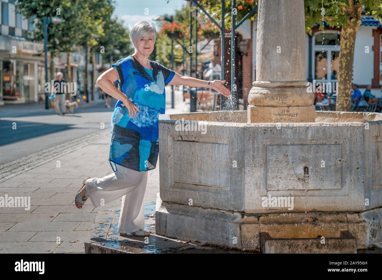 Ein Senior spielt glücklich mit dem Wasser eines Brunnens. Stockfoto