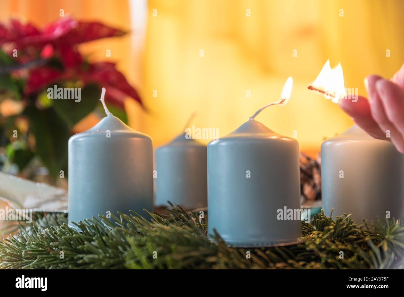 Die erste Kerze auf dem Adventskranz wird mit Streichelzehen angezündet - Nahaufnahme Stockfoto