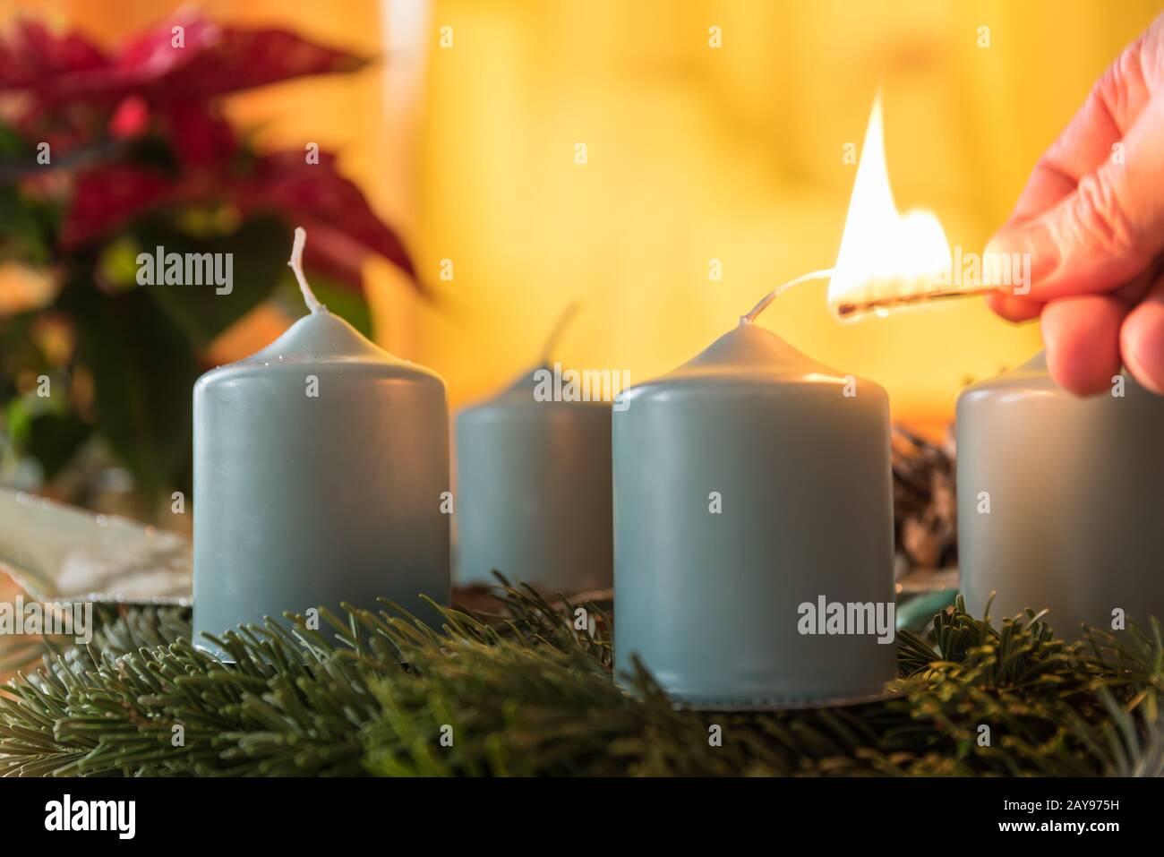 Beleuchten Sie die erste Kerze auf dem Adventskranz mit einem Streichelspiel - Nahaufnahme Stockfoto
