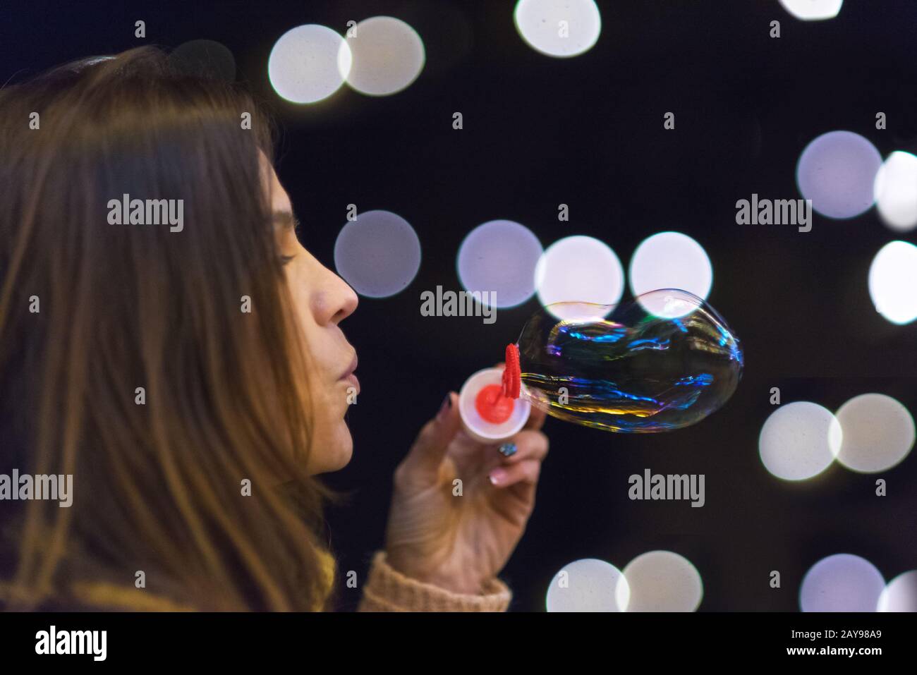 Frau, die Spaß hat, Seifenblasen bei Nachtparty oder Silvesterfeier zu machen Stockfoto