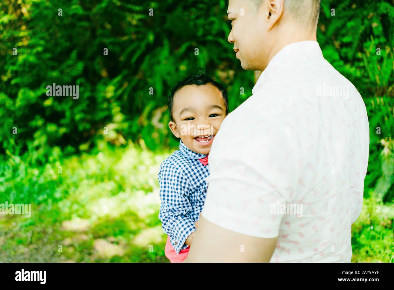 Blick von hinten auf einen Vater, der sein lächelndes Baby trägt Stockfoto