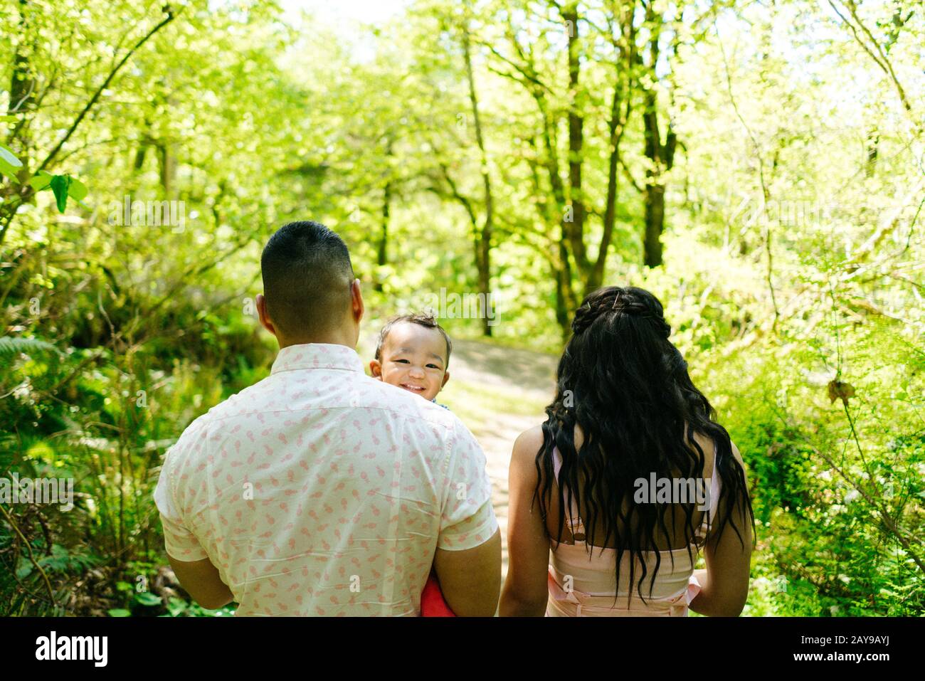 Blick von hinten auf eine dreiköpfige Familie, die durch den Wald geht Stockfoto