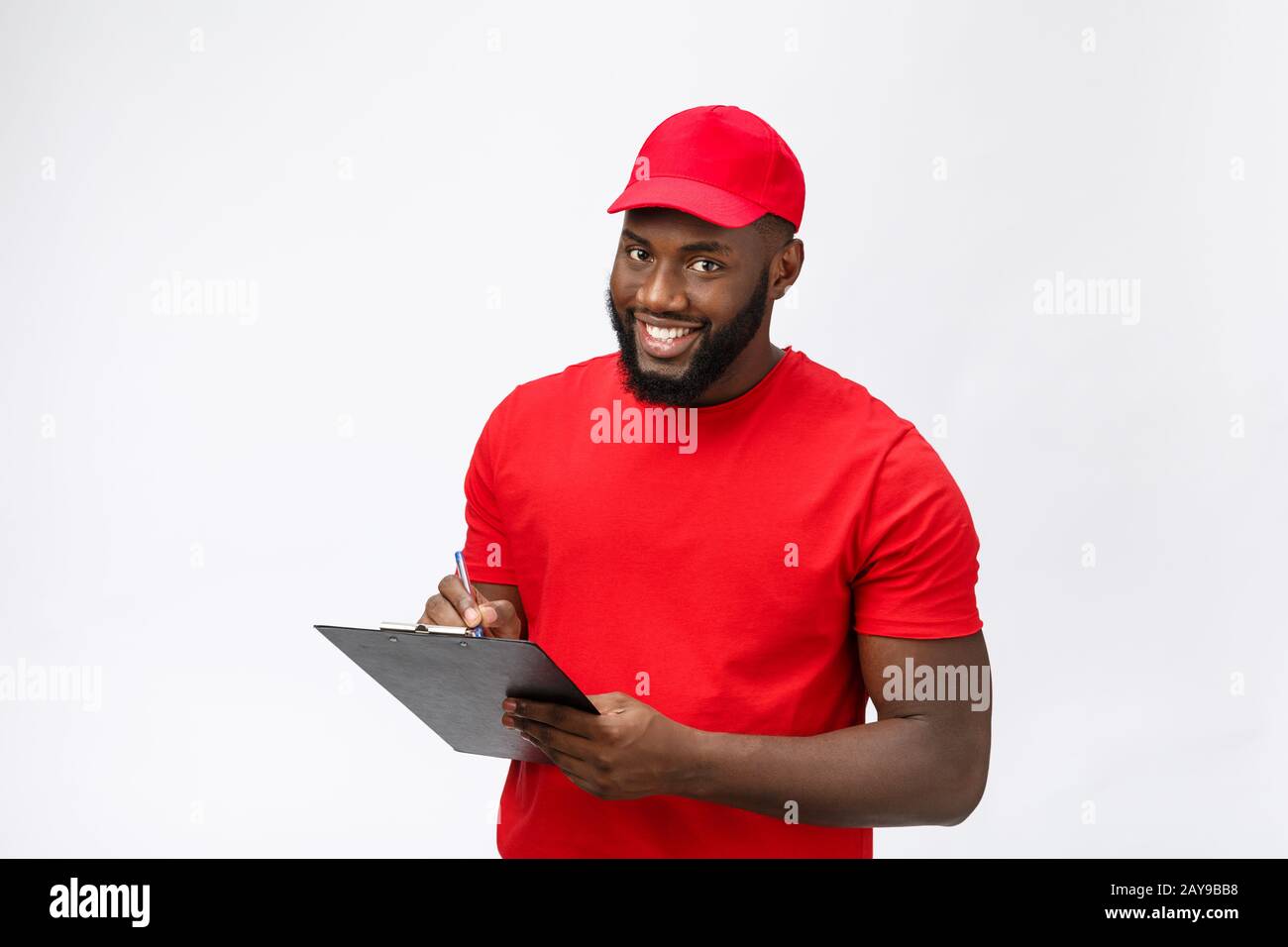 Lieferkonzept - Portrait von Ansehnlichen afroamerikanischen Lieferern oder Kurierern, die ein Bestätigungsformular zur Unterschrift zeigen. ICH Stockfoto