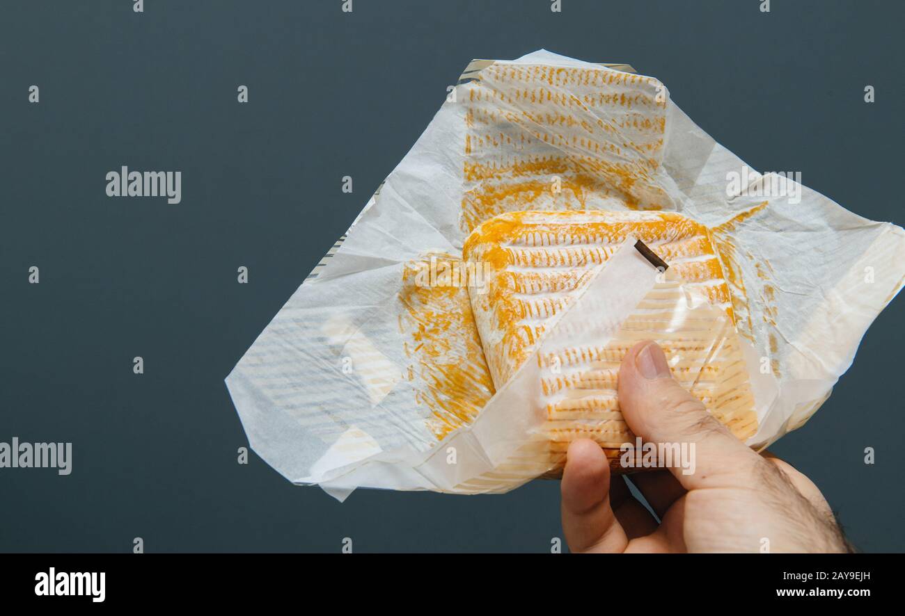 Französische Küche Küchenchef männliche Hand hält vor reinem grauen Hintergrund traditionellen französischen Käse in Papierverpackungen Stockfoto