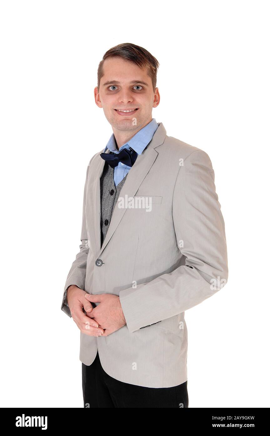 Junger Mann, der in einer grauen Jacke mit Fliege steht Stockfoto